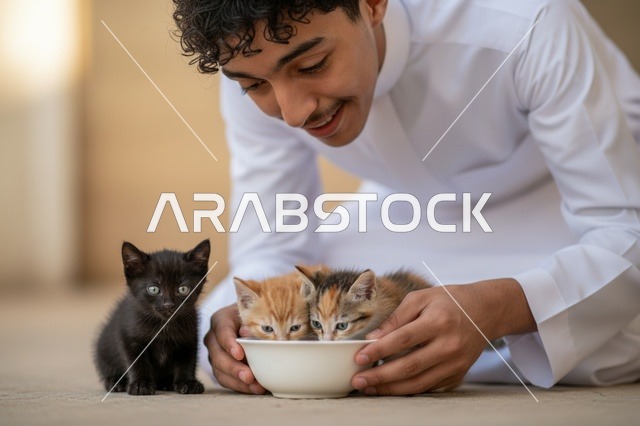 شاب سعودي يرتدي الثوب يطعم قططاً صغيرة