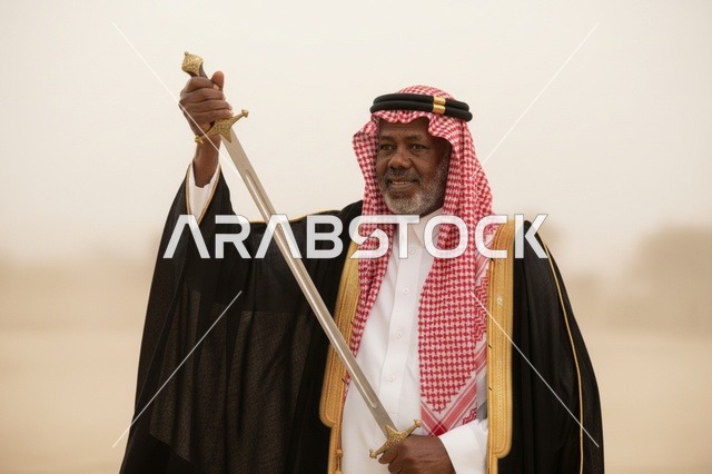 رجل سعودي بالزي التقليدي والبشت يحمل سيفاً