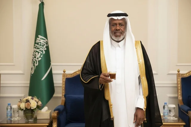 رجل سعودي بالبشت التقليدي يحمل فنجان قهوة عربية