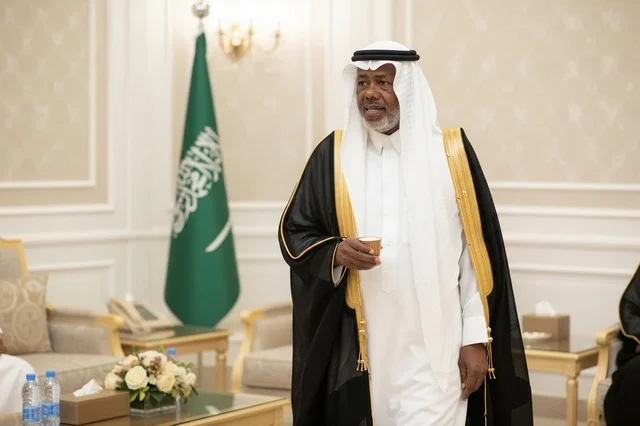 رجل سعودي بالزي التقليدي والبشت مع العلم الوطني