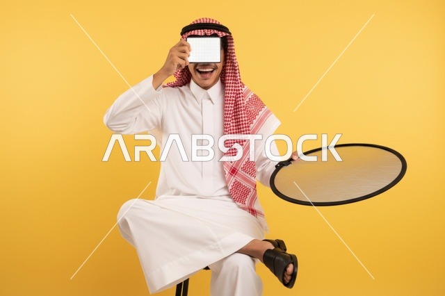 رجل سعودي يحمل جهاز لوحي وعاكس إضاءة