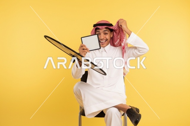 شاب سعودي بالثوب التقليدي مع طبق استقبال فضائي