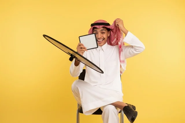شاب سعودي بالثوب التقليدي مع طبق استقبال فضائي