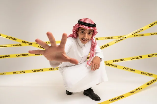 رجل سعودي مع إشارة قف وشريط تحذير