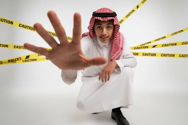 رجل سعودي مع إشارة قف وشريط تحذير