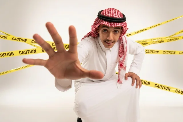 رجل سعودي مع شريط تحذير وإشارة توقف