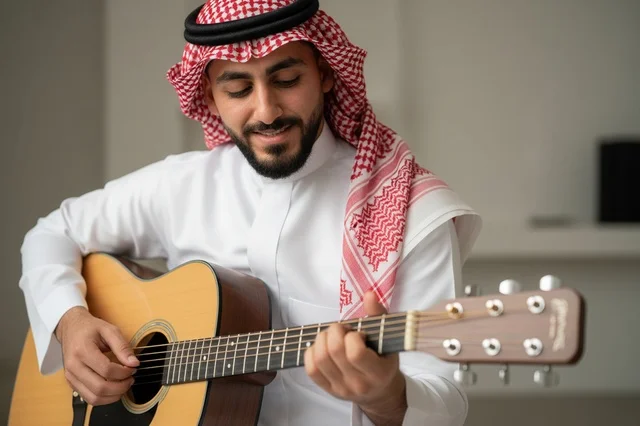 Saudi Man in Traditional Dress Playing Acoustic Guitar