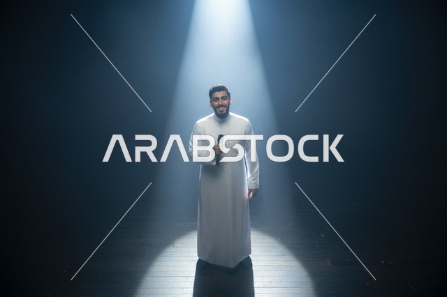 رجل سعودي بالثوب على المسرح تحت الإضاءة