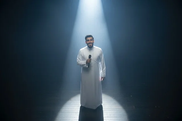 Saudi Man in Thobe on Stage Under Spotlight