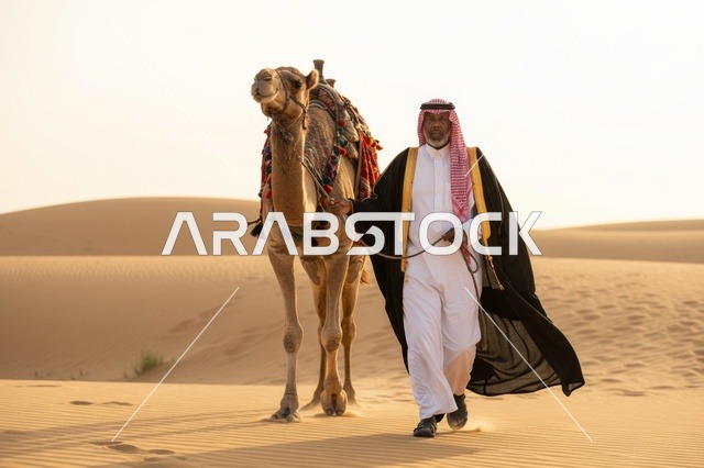 رجل سعودي مع جمل في الصحراء وقت الغروب