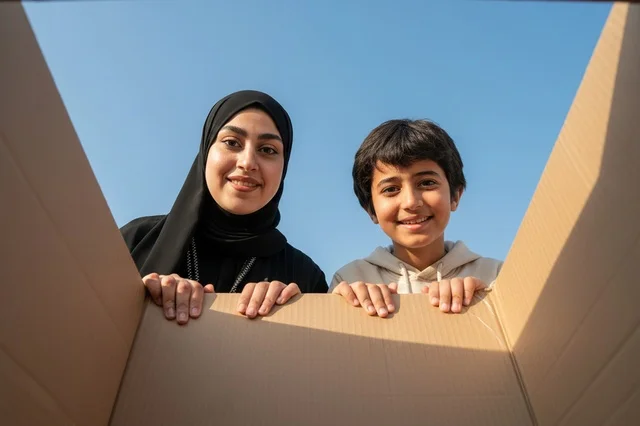 Arab Woman and Boy Looking Into Cardboard Box