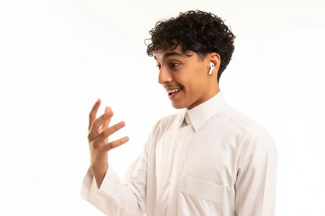 A young Saudi man in a white thobe with wireless headphones in the studio.