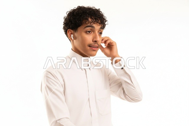 شاب سعودي بالثوب الأبيض يستخدم سماعات لاسلكية