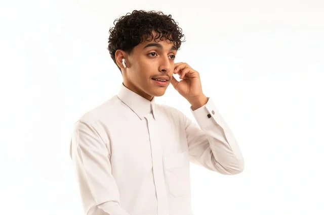 شاب سعودي بالثوب الأبيض يستخدم سماعات لاسلكية