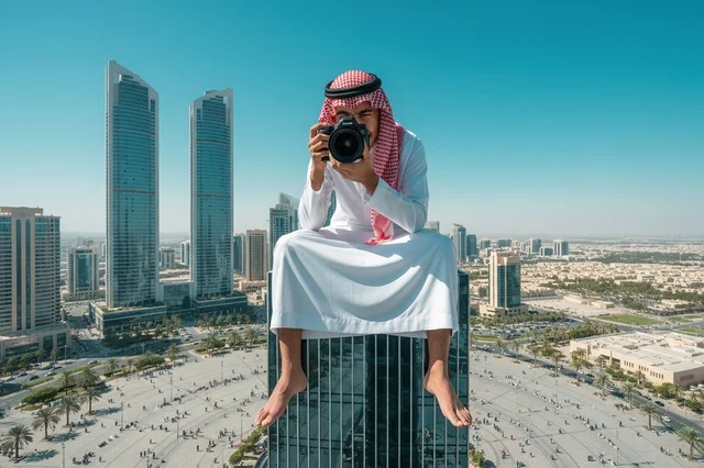 مصور سعودي فوق ناطحة سحاب يطل على أفق المدينة
