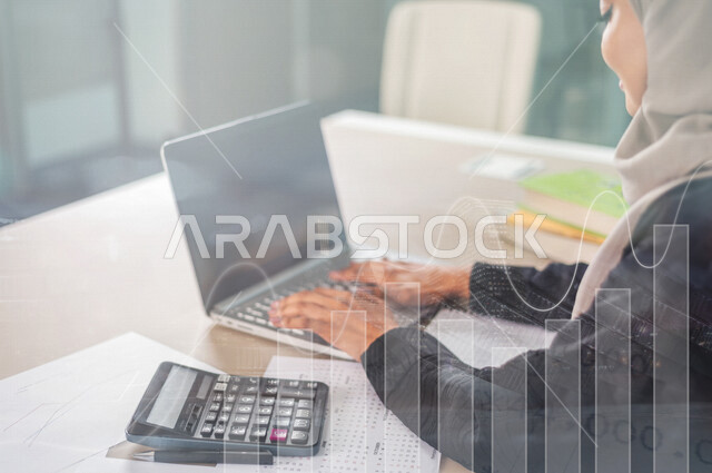 موظفة أنظمة بنكية و قواعد بيانات عربية سعودية خليجية تستخدم الآلة الحاسبة و جهاز الحاسوب لتصنيف و تسجيل المعلومات المالية مدموجة بخلفية لعملات نقدية و رسومات بيانية لصعود و هبوط البورصة المالية ، وظيفة المحاسبة في البنوك