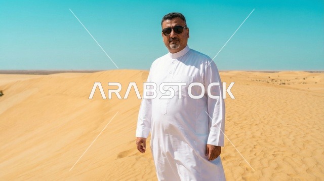 رجل عربي بالثوب الأبيض فوق الكثبان الرملية الصحراوية