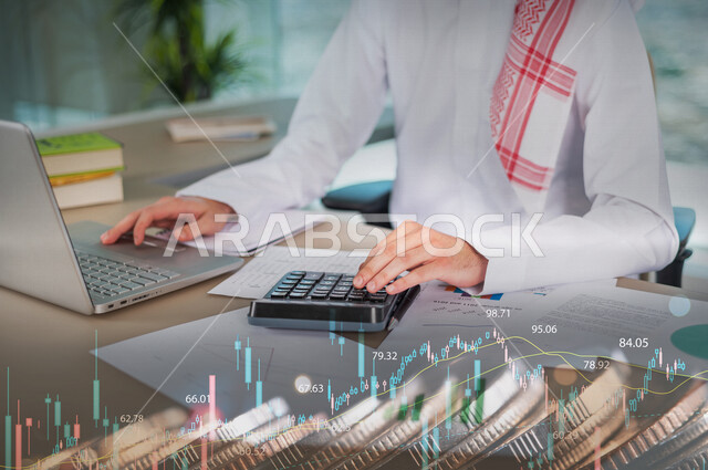موظف أنظمة بنكية و قواعد بيانات عربي سعودي خليجي يستخدم الآلة الحاسبة و جهاز الحاسوب لتصنيف و تسجيل المعلومات المالية مدموجة بخلفية لعملات نقدية و رسومات بيانية لصعود و هبوط البورصة المالية ، وظيفة المحاسبة في البنوك