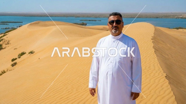 رجل عربي بالثوب الأبيض فوق الكثبان الرملية