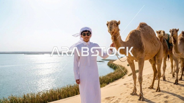 رجل سعودي مع جمل عند بحيرة صحراوية