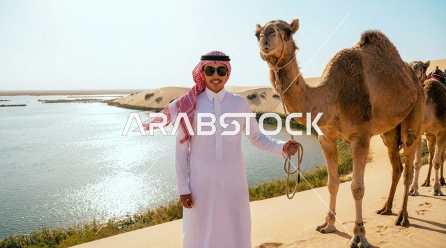 رجل سعودي مع جمل بجوار بحيرة في الصحراء