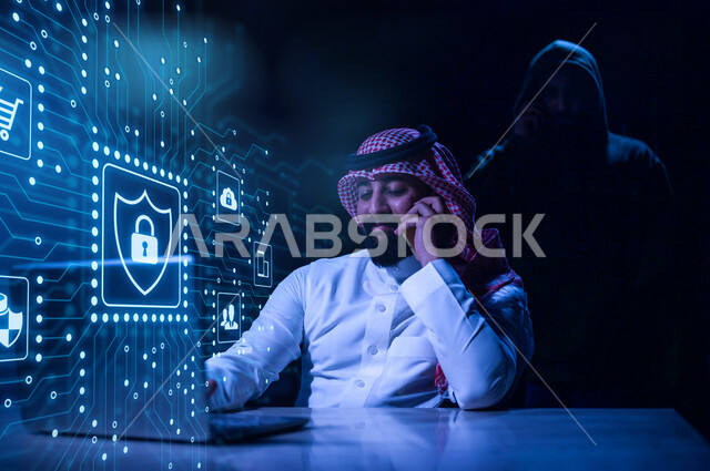 A smiling Saudi Arabian Gulf Arab businessman holds a mobile phone and makes a call, working to protect the laptop from electronic attacks, maintaining personal data and secure access, the concept of IT security