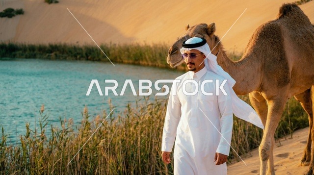 رجل سعودي مع جمل بجانب بحيرة صحراوية