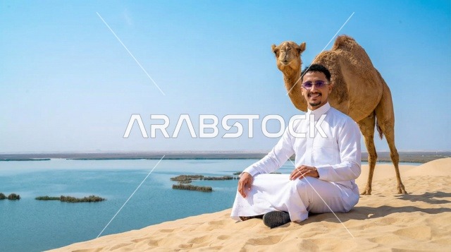 Saudi Man with Camel on Desert Dune Near Water