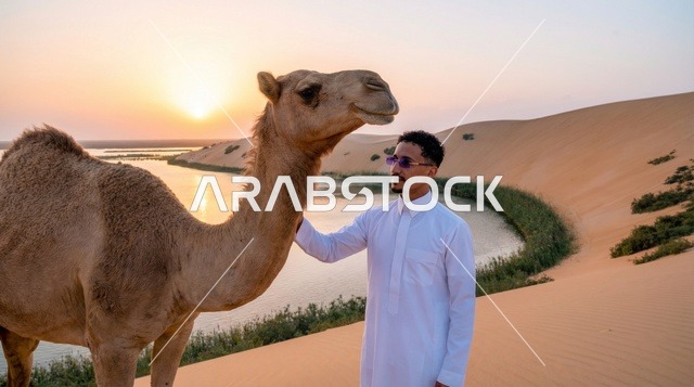 رجل سعودي مع جمل في الصحراء وقت الغروب