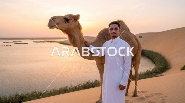 رجل سعودي مع جمل عند بحيرة الأصفر وقت الغروب