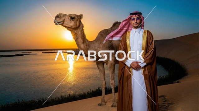 رجل سعودي مع جمل عند بحيرة صحراوية وقت الغروب