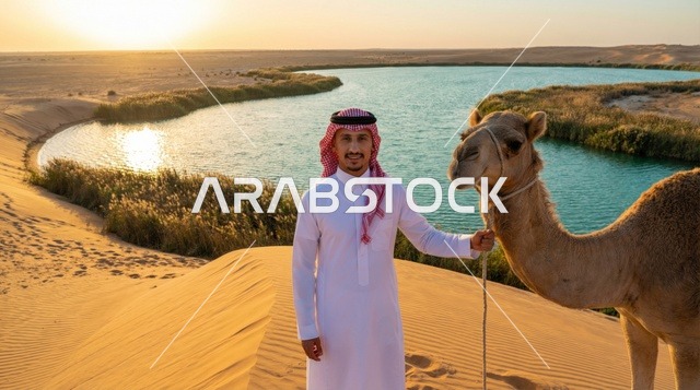 رجل سعودي مع جمل عند بحيرة صحراوية وقت الغروب