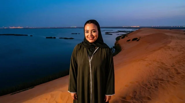 امرأة سعودية بالعباءة فوق كثبان رملية وقت الغسق