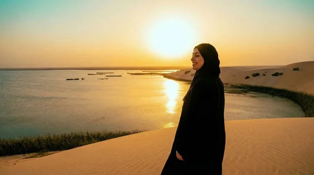 امرأة سعودية بالعباءة عند بحيرة صحراوية وقت الغروب