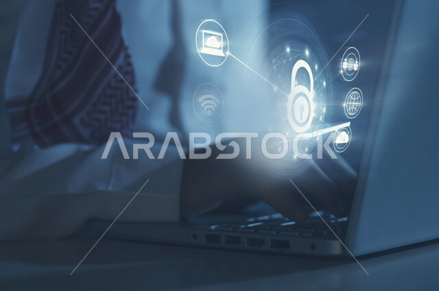 صورة مقربة ليد رجل عربي خليجي سعودي يستخدم الحاسوب المحمول ، أيقونة قفل الأمان مضيئة داخل شبكة عنكبوتية محاطة بمجموعة أيقونات خاصة بالانترنت بتقنية الهولوجرام ثلاثية الأبعاد ، الحفاظ على البيانات الشخصية و الدخول الآمن 