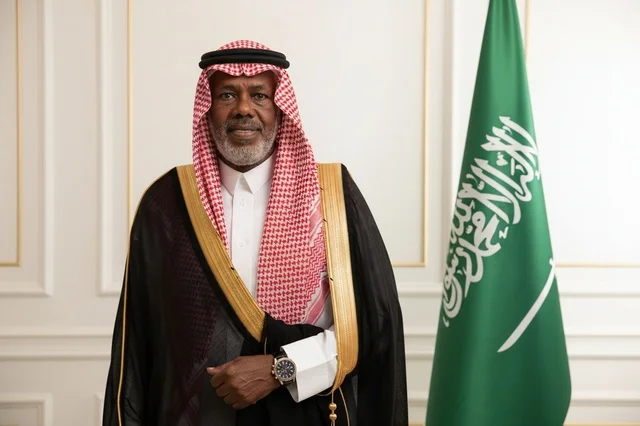 رجل سعودي بالزي الرسمي مع علم المملكة العربية السعودية