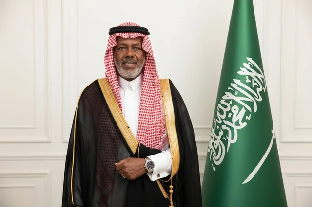 رجل سعودي بالزي الرسمي مع العلم السعودي