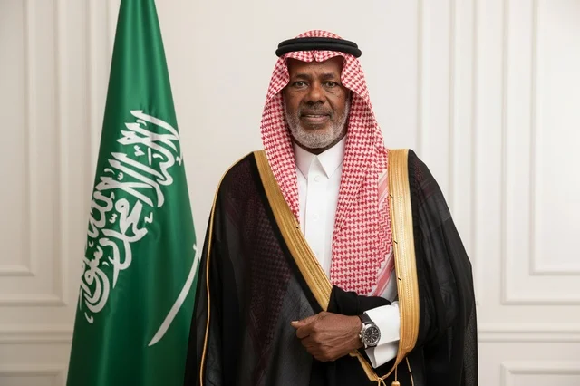 رجل سعودي بالبشت التقليدي بجانب علم المملكة العربية السعودية