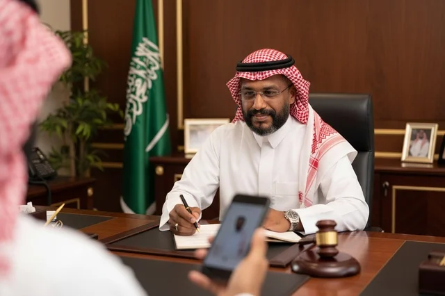 رجل أعمال سعودي في مكتبه مع العلم والمطرقة