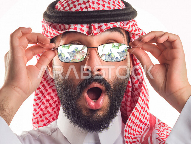 صورة مقربة لرجل أعمال عربي سعودي خليجي ناجح يلبس النظارة الشمسية , تساقط الأوراق النقدية , إيماءات وجه تدل على الدهشة والذهول , الغنى والثراء , النمو والأرباح المالية , مفهوم الاستثمار الناجح . 