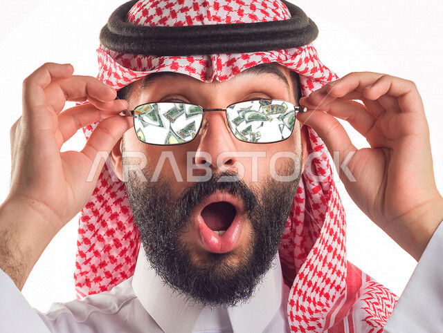 صورة مقربة لرجل أعمال عربي سعودي خليجي ناجح يلبس النظارة الشمسية , تساقط الأوراق النقدية , إيماءات وجه تدل على الدهشة والذهول , الغنى والثراء , النمو والأرباح المالية , مفهوم الاستثمار الناجح . 
