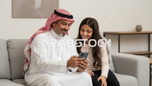 أب سعودي وابنته يستخدمان الهاتف الذكي في المنزل
