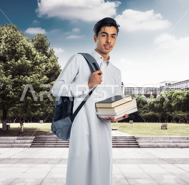 صورة لتلميذ جامعي عربي خليجي سعودي يرتدي الثوب السعودي التقليدي ، يمسك بيده الكتب الجامعية للدراسة ، ايماءات و تعابير للوجه و اليدين مختلفة ، تأدية الواجبات ، التعلم الذاتي , الجد والإجتهاد , التعليم الأكاديمي , الذهاب للجامعة . 