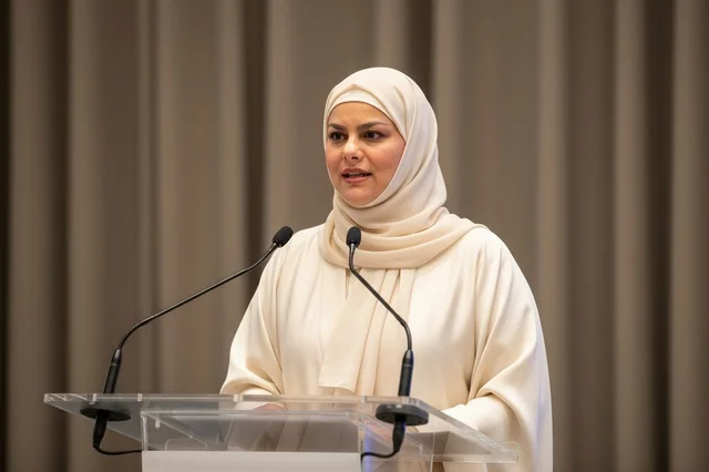 امرأة إماراتية تتحدث خلف منصة بعباءة بيضاء