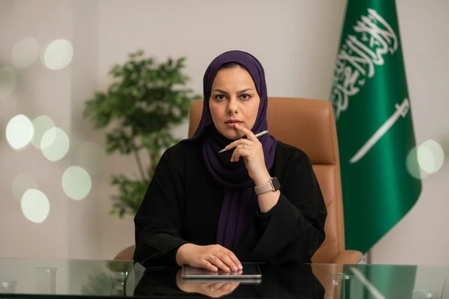 سيدة أعمال سعودية في المكتب مع العلم الوطني