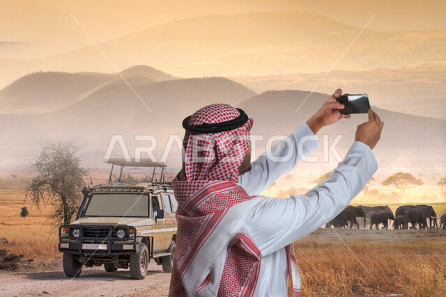 صورة لسائح عربي خليجي سعودي يقوم بالتقاط صورة تذكارية من خلال الهاتف المحمول في سفاري الرياض ، كاميرا امامية، استكشاف الحياة البرية  , فعاليات موسم الرياض , رحلة الى محميات طبيعية ,أنشطة ترفيهية سياحية , قضاء أوقات ممتعة في الإجازة الصيفية .