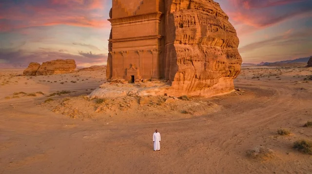 رجل سعودي أمام قصر الفريد في العلا وقت الغروب مشهد جوي