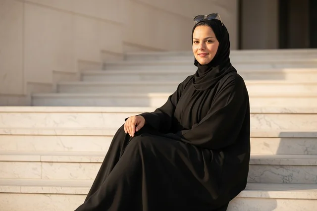 امرأة إماراتية بالعباءة السوداء على درج رخامي