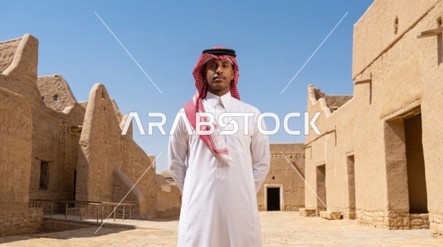 رجل سعودي بالزي التقليدي في قرية تراثية طينية