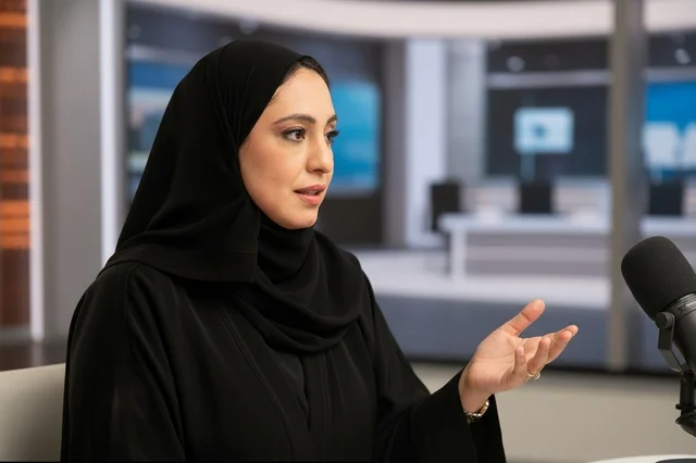 امرأة إماراتية تتحدث في استوديو إعلامي مع ميكروفون